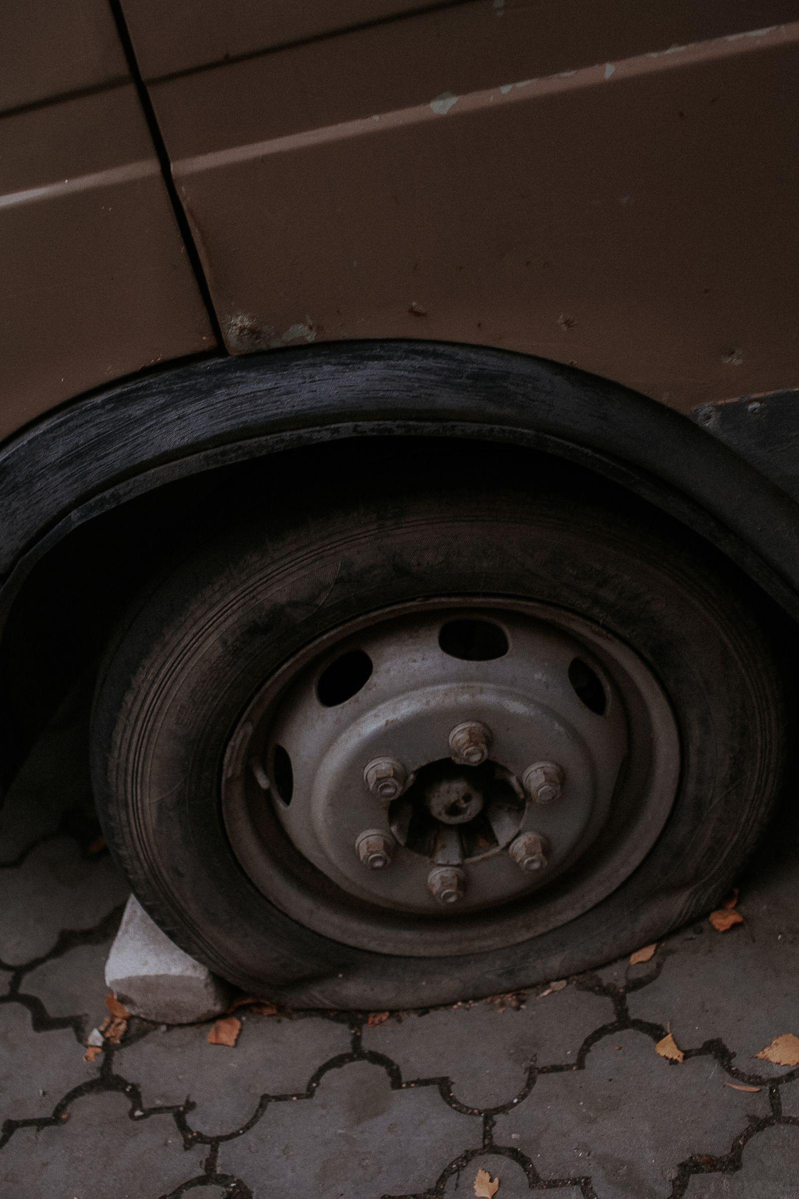 Pneu de carro furado e murcho estacionado sobre pavimento